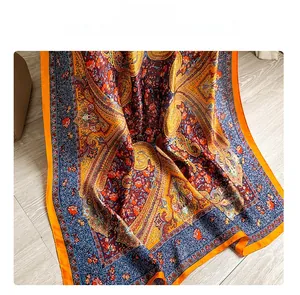 Detailed close-up of orange and navy blue paisley print silk scarf on a wooden surface