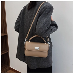 Close-up of khaki leather square bag with silver turn-lock and lychee texture detail