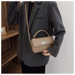 Close-up of brown litchi pattern leather handbag with silver rotating lock and handle