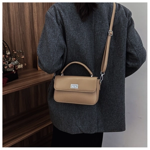 Detail of khaki litchi grain leather bag with silver metal swivel lock and top handle