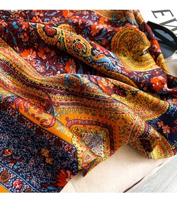 Macro shot of paisley floral print silk scarf with smooth satin finish and vivid colors