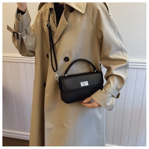 Detail of minimalist black leather crossbody bag with silver twist lock and textured finish
