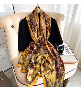 Detail of yellow paisley floral silk shawl draped over a sofa with stylish accessories