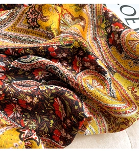 Detail of bohemian paisley floral print silk scarf with luxury satin texture and vibrant colors