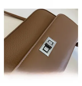 Detail of brown leather bag showing pebbled texture and silver metal twist lock closure