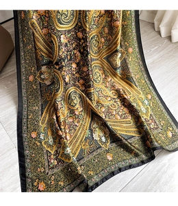 Detailed view of paisley and floral print on vintage style silk scarf with golden tones