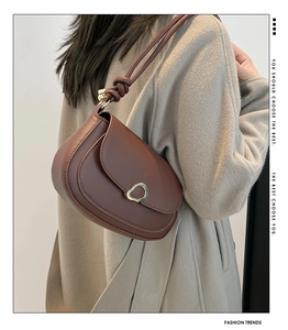 Side view of a vintage dark brown saddle bag with gold buckle and knot strap detail
