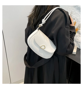 Detail of white leather saddle bag with gold metal ring buckle and knotted strap on black coat