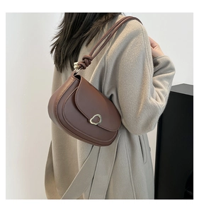 Detail of dark brown saddle bag with gold metal buckle and knotted strap on gray coat