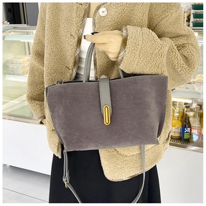 Detail of grey suede tote bag with golden clasp and adjustable shoulder strap on model