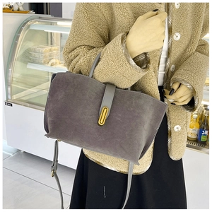 Detail of grey frosted suede tote bag with gold oval lock and adjustable shoulder strap
