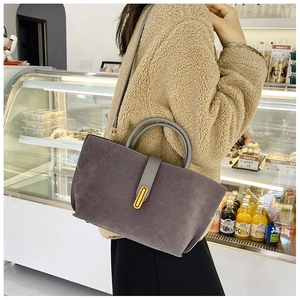Detail of dark grey suede tote bag with golden oval buckle shown on model shoulder