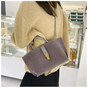 Detail of dark grey suede tote bag with golden metal buckle and leather strap on a model