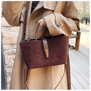 Close-up of deep brown suede tote bag with golden oval buckle and sleek leather handle