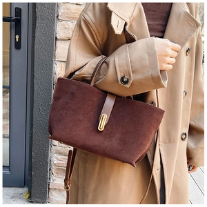 Close-up of vintage brown suede tote bag with gold metal clasp on a khaki trench coat