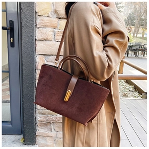 Detailed view of dark brown suede tote bag with elegant gold oval metal clasp detail