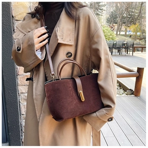 Detail of burgundy frosted suede tote bag with golden metal buckle and sleek leather handle