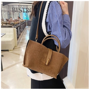 Detail of dark brown frosted leather tote bag with gold metal buckle and dual handles