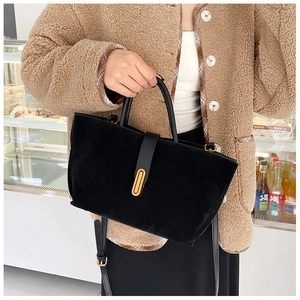 Detail of black suede tote bag with golden metal buckle and adjustable shoulder strap