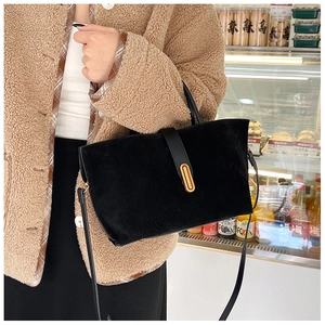Detail of black frosted tote bag with gold metal clasp on a stylish winter outfit