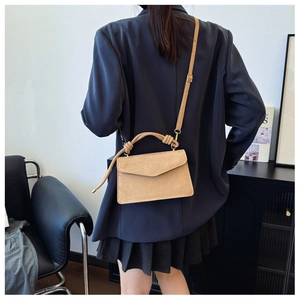 Detail of beige frosted leather crossbody bag with unique knotted handle and shoulder strap