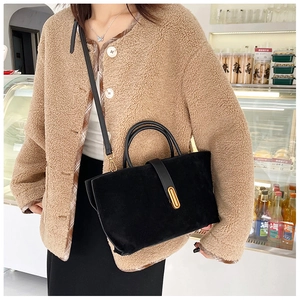 Detail of vintage matte black tote bag with gold buckle on a model in fleece coat