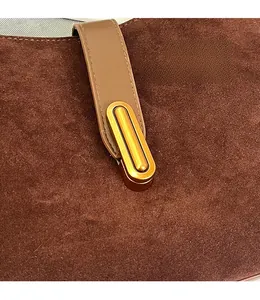 Close-up of the golden metal oval lock and brown matte leather strap on a tote bag