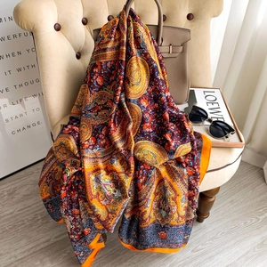 Elegant paisley floral print silk scarf displayed as a stylish wrap on a chair