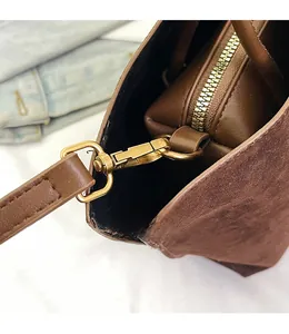 Detail of detachable gold hardware hook and zipper on brown matte tote bag