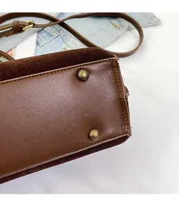 Close-up of vintage bronze metal studs on brown matte leather bag for wear resistance