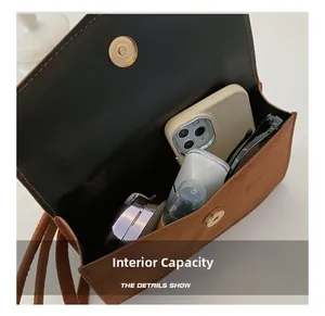 Internal capacity of the brown suede crossbody bag showing daily items inside