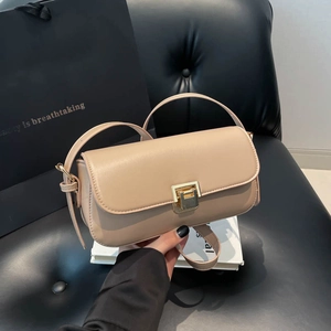 Sac à main minimaliste en cuir beige avec fermoir doré, présenté tenu à la main