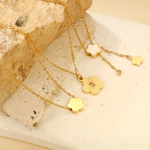 Elegante goldene Edelstahl-Blumenanhänger mit Perlmutt auf einer Steinpräsentation