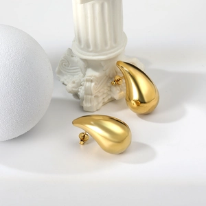 Minimalist gold teardrop earrings with a polished mirror finish on classic white pedestals