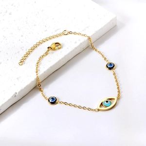 Golden Evil Eye bracelet with enamel charms and adjustable lobster clasp on stone stand