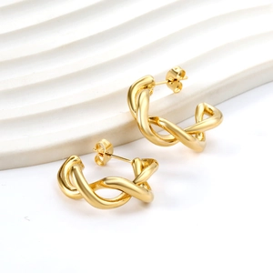 Boucles d'oreilles créoles dorées torsadées en C sur présentoir en marbre chic