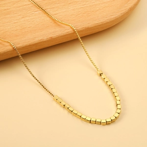Elegant gold cube bead necklace with polished finish on minimal wooden background