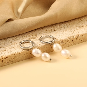 Elegant silver metal hoop earrings with double white baroque pearl drops on stone background