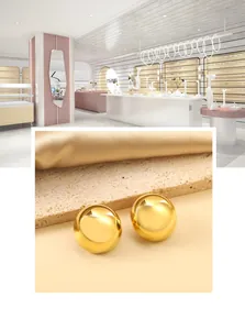 Detailed macro view of polished golden dome stud earrings on a textured stone surface
