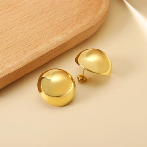 Polished gold semi-circle stud earrings in minimalist metal style on a wooden tray
