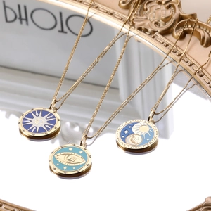 Colliers tarot en or avec pendentifs émaillés soleil et œil sur surface miroir