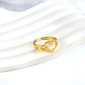 Minimalist gold heart-shaped open ring with intricate twisted wire design on white pedestal