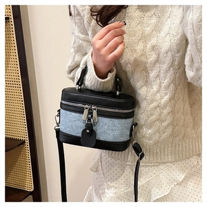 Detail of a cylindrical crossbody bag in leather and denim patchwork on a model