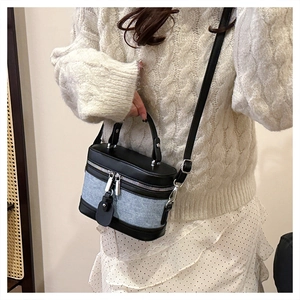 Cylindrical contrast bag in denim and leather shown styled with a knit sweater