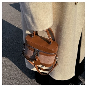 Detail of a vintage cylindrical box bag with textured canvas and smooth leather stitching