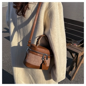 Brown patchwork cylinder box bag shown on model for size perspective in outdoor light