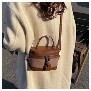 Detail of vintage brown canvas and leather cylinder bag with silver metal zippers