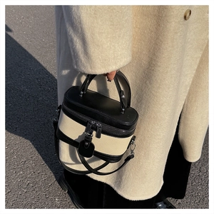 Detailed close-up of retro black and white patchwork box bag with a top handle and leather strap
