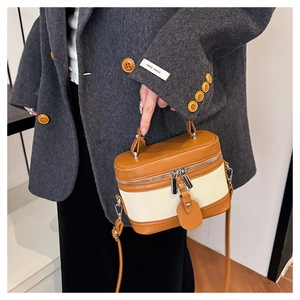 Detail of a cylindrical canvas and brown leather bag with metallic hardware details