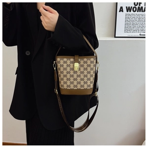 Close-up of vintage bucket bag with monogram pattern and brown leather trim on a model
